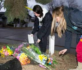 Unidentified women leave flowers at the scene of the multiple fatal stabbing in northwest Calgary, Alberta on Tuesday, April 15. (AP Image)