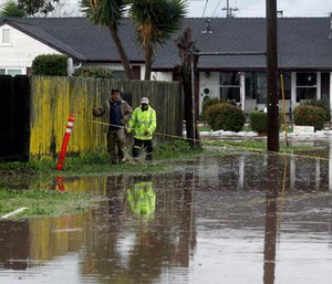 Residents walk down a flooded road on Monday, Feb. 20, 2017, in Salinas, Calif. (Nic Coury/Monterey County Weekly via AP)