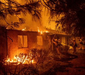 Firefighters work to keep flames from spreading through the Shadowbrook apartment complex as a wildfire burns through Paradise, Calif., on Friday, Nov. 9, 2018.