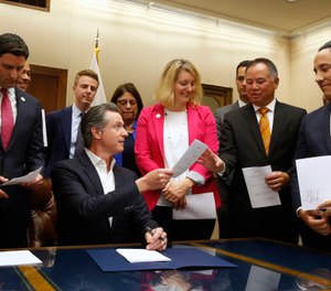 alifornia Gov. Gavin Newsom, seated hands Assemblyman Phil Ting, D-San Francisco, second from right, a copy of his bill that Newsom signed at the Capitol in Sacramento, Calif., Friday, Oct. 11, 2019. (AP Photo/Rich Pedroncelli)