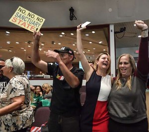 David Hernandez, left, Genevieve Peters, center, and Jennifer Martinez celebrate after the Orange County Board of Supervisors voted to join the U.S. Department of Justice lawsuit against the State of California's sanctuary cities law.