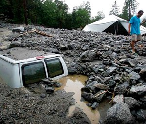 An official of Forest Home Christian Conference Center in Forest Falls, Calif., inspects damage on the property following thunderstorms on Sunday, Aug. 3, 2014. About 1,500 residents of Oak Glen, and another 1,000 residents of Forest Falls in the San Bernardino Mountains were unable to get out because the roads were covered with mud, rock and debris, authorities said. (AP Photo/The Press-Enterprise, David Bauman)