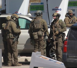 Royal Canadian Mounted Police officers surround a suspect at a gas station in Enfield, Nova Scotia.