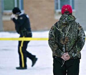 A man holds a rosary as police investigate the scene of a shooting at the community school in La Loche, Saskatchewan.