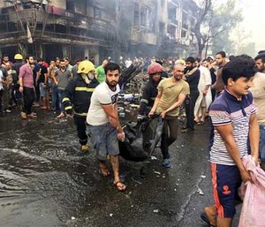 Iraqi firefighters and civilians carry bodies of victims killed in a car bomb at a commercial area.