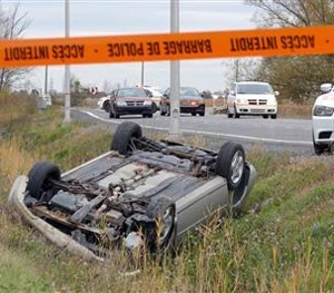 A car is overturned in the ditch in a cordoned off area in St-Jean-sur-Richelieu, Quebec on Monday Oct. 20, 2014.