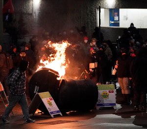 A trash can burns as people take part in a protest against police brutality, late Sunday, Jan. 24, 2021, in downtown Tacoma, Wash., south of Seattle. (AP Photo/Ted S. Warren)