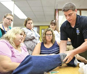 Sean Marquis, associate EMS medical director for Mercy Health System, demonstrates how to apply a tourniquet during a casualty care training session at Darien Elementary School on Monday.