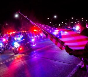 Rick Beckner salutes the procession for El Paso County Sheriff's Deputy Micah Flick while holding his flag on the side of the road outside of the El Paso County Coroner's Office, Monday, Feb. 5, 2018, in Colorado Springs, Colo.