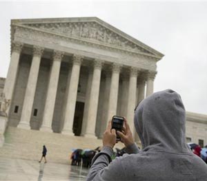 This April 29, 2014 file photo shows a Supreme Court visitor using his cellphone to take a photo of the court in Washington.