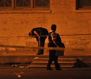 In this Sept. 20, 2013 file photo, Chicago police detectives investigate the scene where a number of people were shot in a city park.