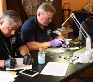 Forensic firearms examiners inspect weapons turned in by residents in a gun buy-back program (Photo/ Chicago Police Department via Associated Press)
