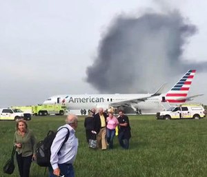 In this photo provided by passenger Jose Castillo, fellow passengers walk away from a burning American Airlines jet that aborted takeoff and caught fire on the runway at Chicago's O'Hare International Airport on Friday, Oct. 28, 2016.