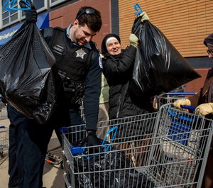 Officer Frank Johnson works with Sister Jaime Mitchell, right, and others to pack bags of food into a wagon on Tuesday, March 24, 2020, at Mission of Our Lady of the Angels in Humboldt Park. (Photo/TNS)