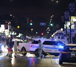 Trick-or-treaters walk past a crime scene where a seven-year-old girl was shot while trick-or-treating Halloween night.