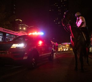 In this Thursday, July 4, 2019 photo, A Chicago Police Department (CPD) officer secures a path for ambulance after reports of stabbings and threatening injuries after the 4th of July celebrations at Chicago's Navy Pier. Police said a false report of gunfire set off a stampede that trampled more than a dozen people. (AP Photo/Amr Alfiky)