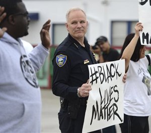 In this photo taken Tuesday, Dec. 9, 2014, Richmond Chief of Police Chris Magnus stands with demonstrators along Macdonald Ave. in Richmond, Calif.