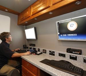 Los Angeles Police Department Internet Crimes Against Children Task Force detective Shannon Geaney demonstrates computer forensics on a hard drive at a mobile lab, after authorities throughout Southern California announce the arrests of more than 275 child predators during a news conference in Los Angeles Thursday, June 26, 2014.