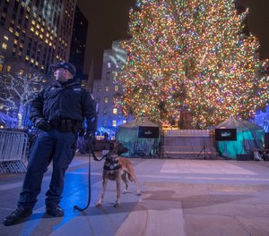 A police officer with a bomb sniffing dog stands next to the Rockefeller Center Christmas tree after the 86th annual Rockefeller Center Christmas tree lighting ceremony, Wednesday, Nov. 28, 2018, in New York.