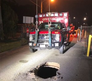 An Orlando Fire Department ambulance had to be lifted up and towed after becoming stuck in a hole initially suspected to be a sinkhole. City officials later clarified that the hole was actually the result of a caved-in stormwater or wastewater line. (Photo/Orlando Fire Department)