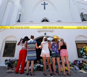 In this June 18, 2015, file photo, a group of women pray together at a makeshift memorial on the sidewalk in front of the Emanuel AME Church, in Charleston, S.C.