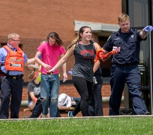 In a May 25, 2016 file photo, an emergency worker directs a volunteer with simulated injuries during a training exercise for an active shooter at Hopewell Elementary School, in West Chester, Ohio.