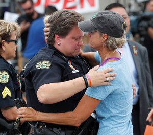 In this June 12, 2017 file photo, Orlando police department Officer Alison Clarke is embraced by Christine Gogicos while visiting the memorial outside the Pulse Nightclub on the one-year anniversary of the shooting in Orlando. (Photo/TNS)