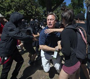 KCRA television reporter Mike Luery runs away from members of the group called ANTIFA Sacramento (Anti-Fascism Action), at the California state Capitol in Sacramento, Calif., Sunday, June 26, 2016.