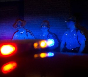 Police officers are illuminated by patrol car lights, Saturday, May 23, 2015, in Cleveland.
