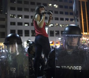 A protestor films riot police as they advance on a small march against the acquittal of Michael Brelo, Saturday, May 23, 2015.