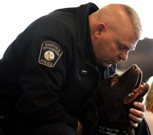 Chief Andrew Wood of the Hancock Police Department interacts with his department’s comfort dog, Rookie.