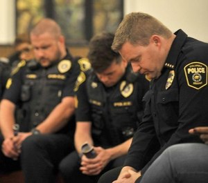 Columbus Police Chief Geoff Jones (right) prays with officers and church members at the Second Baptist Church. Jones has been working with the city to implement a series of community-based policing policies. (Photo/TNS)