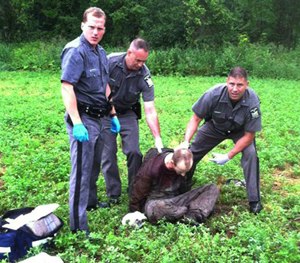 Police stand over David Sweat after he was shot and captured near the Canadian border Sunday, June 28, 2015, in Constable, N.Y. (AP Image)