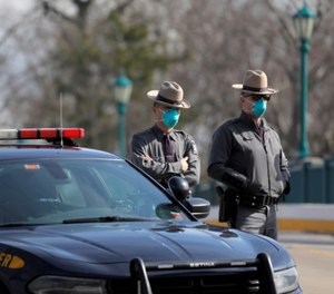 Police officers wear protective masks at the checkpoint of a testing facility for the novel coronavirus in New Rochelle, N.Y., on Monday, March 16, 2020.