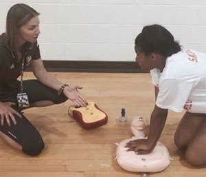 Teacher Andrea Padelsky instructs a student on proper chest compressions and use of an AED.