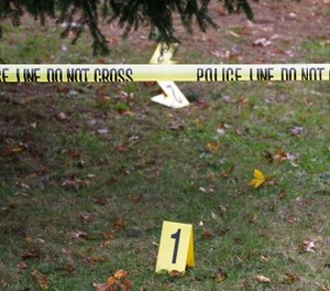 Evidence markers are visible behind police crime scene tape in Weymouth, Mass., Friday morning, Nov. 11, 2011.
