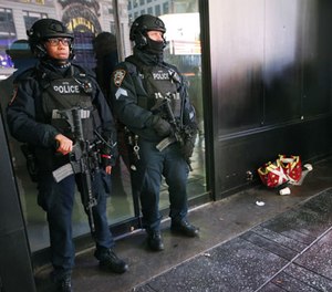 Heavily armed counterterrorism officers take shelter from the rain beneath an overhang in Times Square, Thursday, Dec. 29, 2016, in New York.