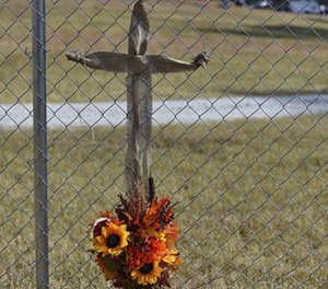 A cross prepared by JoAnn McKinney, a local resident, hangs on the fence of Todd Kohlhepp's property in Woodruff, S.C. Sunday, Nov. 6, 2016. (AP Photo/Richard Shiro)