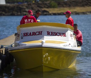 Honolulu Fire Department search and rescue members sit on a docked boat at a boat harbor.