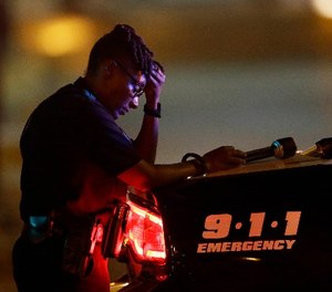 In this July 8, 2016, file photo, a Dallas police officer, who did not want to be identified, takes a moment as she guards an intersection in the early morning after a shooting in downtown Dallas. (AP Photo/LM Otero, File)