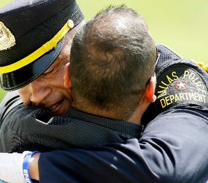 A Dallas police officer gets a hug after an honor guard ceremony for Dallas police officer Patrick Zamarripa at Dallas-Fort Worth National Cemetery in Dallas, Saturday, July 16, 2016.