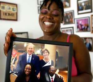 In this June 30, 2017, photo, Shetamia Taylor laughs as she holds a photo in Garland, Texas, of her and her husband, Lavar, bottom right, meeting former President George W. Bush, and Laura.