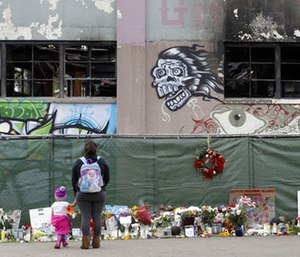 In this Dec. 13, 2016, file photo, flowers, pictures, signs and candles, are placed at the scene of a warehouse fire in Oakland, Calif.