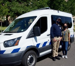 Two civilian healthcare workers with Denver's Support Team Assisted Response program pose with their van.
