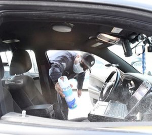 Detroit Neighborhood police officer Dan Robinson sprays down his police vehicle with disinfectant spray before checking that groups of people do not congregate in city parks and playing fields in Detroit, Michigan on April 8, 2020.
