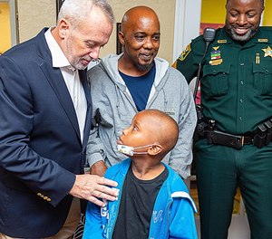 St. Johns County Sheriff David Shoar talks to Arcolia Gilliard Jr., who was surprised by local law enforcement officers with a weeklong trip to Disney World. (Photo/Peter Willott/The Record/TNS)