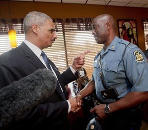 In this Aug. 20, 2014 file photo, Attorney General Eric Holder talks with Capt. Ron Johnson of the Missouri State Highway Patrol at Drake's Place Restaurant in Florrissant, Mo. (AP Image)