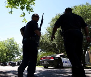 Dallas Police walk a neighborhood a block away from a shooting in Dallas.