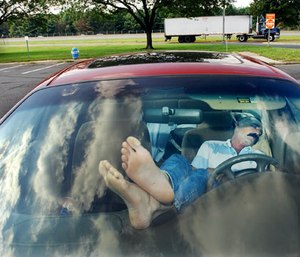 In this Sept. 25, 2003 file photo, an unidentified man rests his feet on the dashboard as he takes nap at a New Jersey Turnpike rest stop in Mount Laurel, N.J. (AP Photo/Daniel Hulshizer, File)