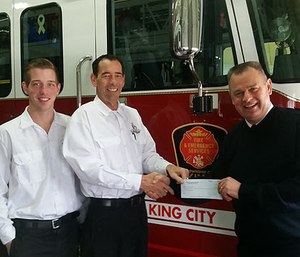 Fire Chief James Wall of King Fire and Emergency Services in King City (Ont.) accepts the DVW grant from franchisee Tyler Johnson, at center, and DVW technician Leighton Johnson of Dryer Vent Wizard of York, Ontario.